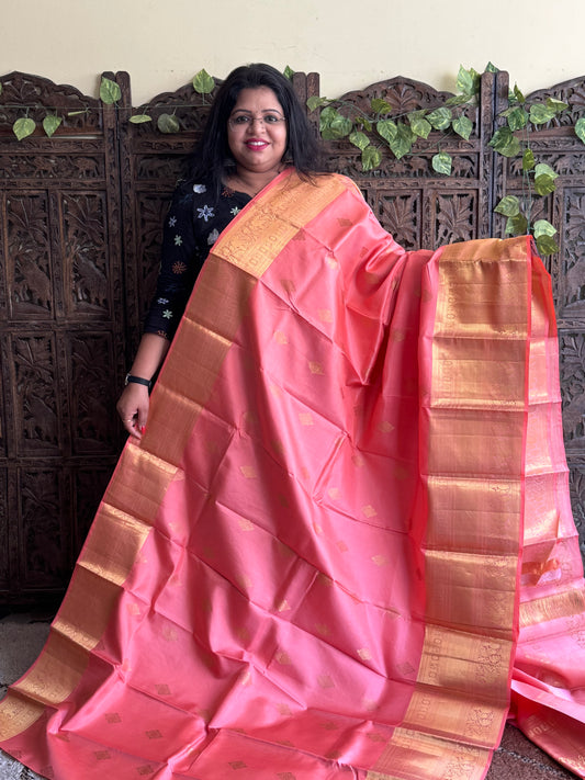 Pure Kanjivaram Silk Saree Peach Colored Elegantly Paid with a Gold Zari Border.