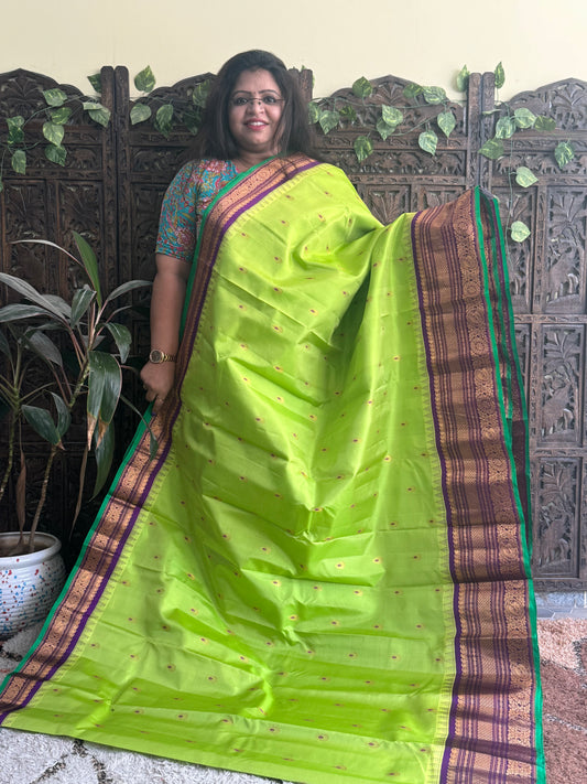Gadwal Pattu Saree Parrot Green colored saree complemented with a Purple Zari border - Sampradaya Designer Studio