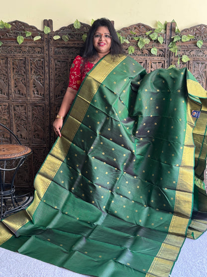 Pure Kanjivaram Silk Saree Bottle Green Colored Elegantly Paid with a Gold Zari Border.