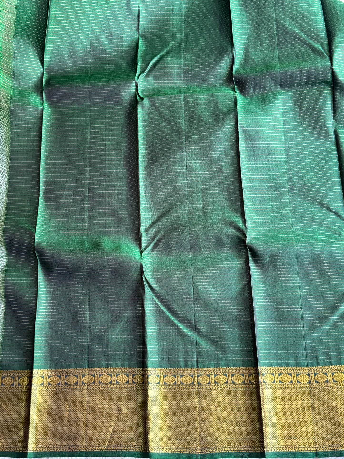 Pure Kanjivaram Silk Saree Bottle Green Colored Elegantly Paid with a Gold Zari Border.