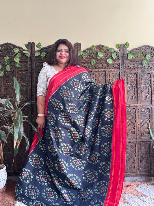 Ikkat Pattu Saree Black colored complemented with a Red Patola border. - Sampradaya Designer Studio