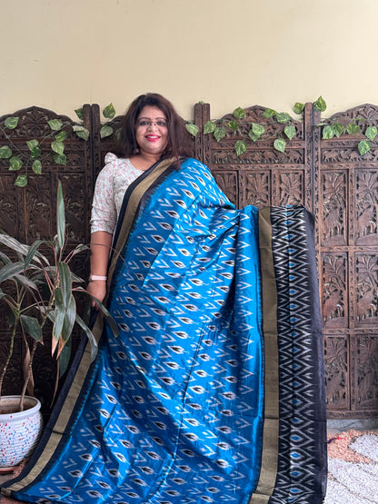 Ikkat Pattu Saree Sky Blue colored complemented with a Black Patola border. - Sampradaya Designer Studio