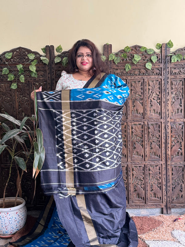 Ikkat Pattu Saree Sky Blue colored complemented with a Black Patola border. - Sampradaya Designer Studio