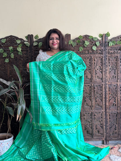 Ikkat Pattu Saree Parrot Green colored complemented with a Patola border. - Sampradaya Designer Studio